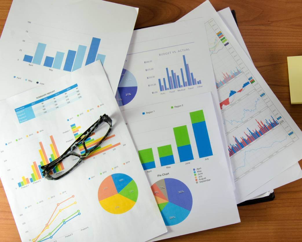 A desk with many papers displaying charts and graphical data